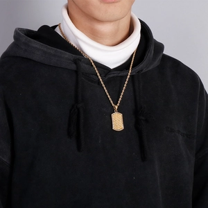 Close-up of gold dog tag pendant with sparkling pavé crystals on a twisted rope chain