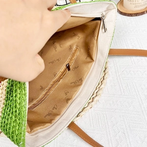 Green and natural straw woven tote bag with internal zipper pocket and brown lining
