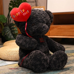 Detailed close-up of dark grey curly teddy bear with a red heart and happily met embroidery