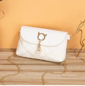 Detail view of a white quilted crossbody bag with cat ear metal ring and pearl tassels