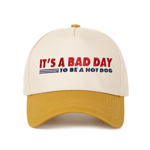 Detail of five-panel baseball cap with red and blue embroidery on cream and yellow fabric