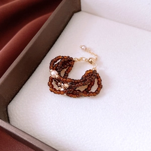 Detail of amber glass beaded multi-layer ring with pearls and golden lobster clasp