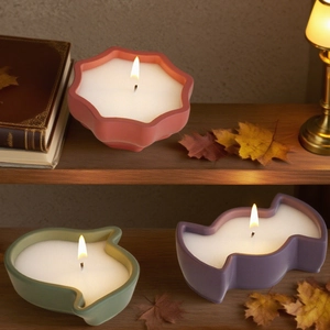 Three colorful star and heart-shaped scented candles lit on a vintage wooden shelf