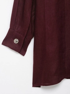 Detail of burgundy linen suit fabric showing cuff texture and silver matte button