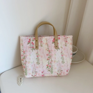 Close-up of pink floral tote bag with sturdy brown PU handles and reinforced metal rivets
