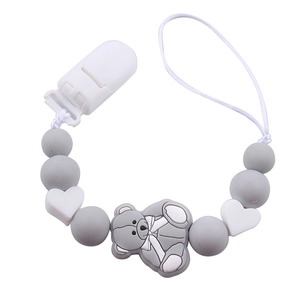 Detail of grey and white silicone pacifier clip with cartoon bear and heart beads
