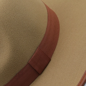 Macro view of khaki felt fedora hat showing dark brown ribbon and leather bound edge