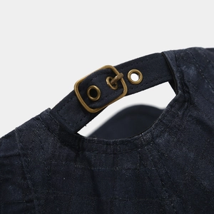 Detail of navy blue beret featuring vintage bronze metal buckle and textured grid fabric