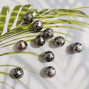 Detail of faceted silver metallic disco beads for DIY jewelry making on leaf background