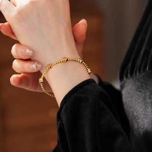 Dettaglio del bracciale a fiori placcato oro 18k con zirconi sul polso di una donna