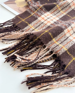 Gros plan détaillé des franges et de la texture douce du foulard à carreaux marron