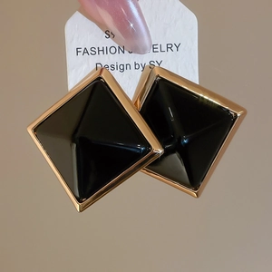 Vue macro de boucles d'oreilles rétro françaises avec cadre doré et pyramide en résine noire