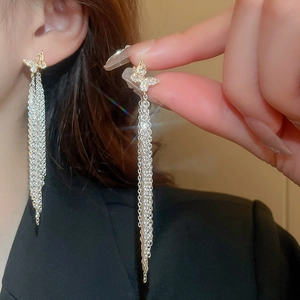 Détail de boucles d'oreilles à longs glands avec clous papillons en diamants étincelants