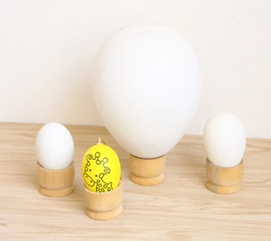Detail of wooden egg holders with a giraffe painted egg and assorted white faux eggs