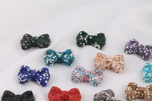 Close-up of sparkling rhinestone bow charms in various colors on white fabric