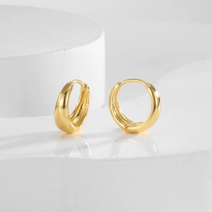 Élégantes boucles d'oreilles créoles dorées sur une plateforme blanche minimaliste