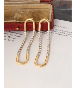 Detailed macro view of gold U-shaped earrings with cubic zirconia in a velvet jewelry box