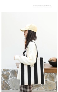 Detailed view of a striped canvas tote bag with contrast shoulder straps and logo detail