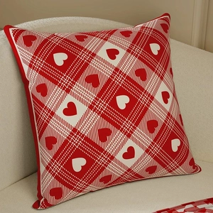 Christmas red plaid heart pillow cover on cream sofa with a warm festive holiday atmosphere