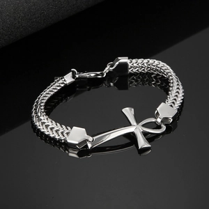 Makroaufnahme von silberner Gliederkette mit Ankh-Kreuz Anhänger auf dunklem Hintergrund