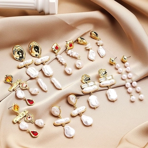 Elegant collection of long baroque pearl earrings with rhinestones on satin background