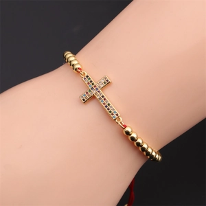 Detailed view of gold plated beaded bracelet with rainbow zircon cross on wrist