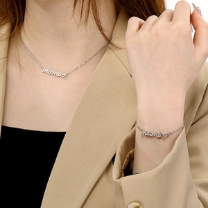 Detailed view of silver mami letter and heart charms on necklace and bracelet set