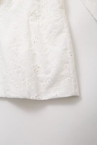 Close-up of intricate white floral embroidery and hollow-out detailing on cotton fabric