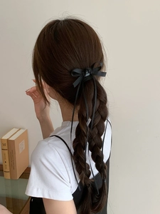 Détail d'un nœud en ruban noir avec rose, porté sur une coiffure à tresse élégante