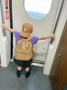 Close-up of a brown kids baseball cap with letter P and matching backpack in a train