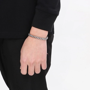 Detail of silver stainless steel curb chain bracelet with OT buckle on male wrist