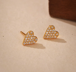 Macro shot of gold heart stud earrings featuring micro-pave clear zircon settings
