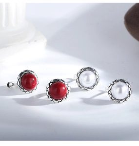 Macro view of vintage silver button earrings with red and white pearls and mesh detail