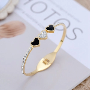 Dettaglio macro del bracciale a cuore dorato con smalto nero e pietre in zircone pavé