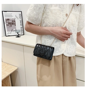 Detail of girls black heart-quilted crossbody bag with elegant gold chain strap