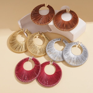Detailed close-up of woven metallic hoop earrings in brown, gold, silver, and red colors