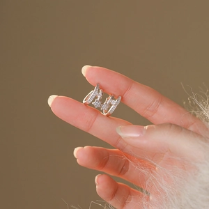 Macro detail of silver star and circle ear cuffs with zircon stones held in hand