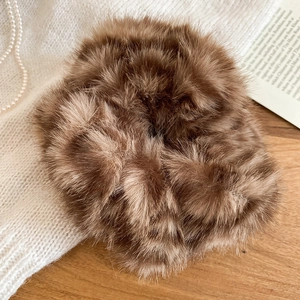 Dettaglio dell'elastico per capelli in peluche marrone su scrivania in legno