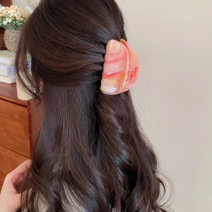 Detailansicht der großen Haarklammer mit Marmor-Effekt in Orange-Rosa am Haar