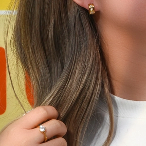 Close-up of gold plated square hoop earrings with cubic zirconia on a female model