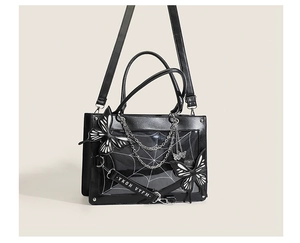 Detail of black PU tote bag with spider web pattern, large bows and metallic chains