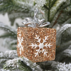 Champagne gold glitter gift box Christmas ornament with snowflakes on snowy pine branch