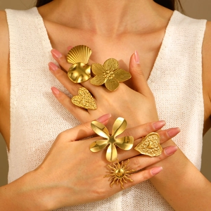 Detailed view of model wearing gold textured flower, heart and sun statement rings