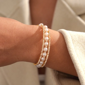 Detailed view of triple-layered pearl and diamond bracelet on a woman wrist