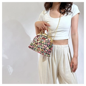Floral print shell handbag with golden metal frame and chain strap on female model