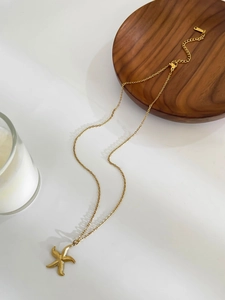 Detailed macro view of a gold starfish pendant necklace with lobster clasp and extension chain