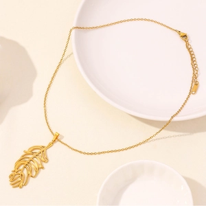 Detailed view of gold hollow leaf pendant and lobster clasp on fine stainless steel chain