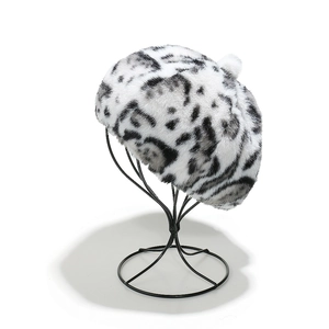 Detail view of plush faux fur leopard print beret on a black display stand