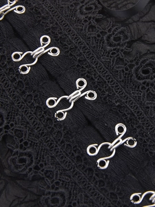 Macro shot of silver metal hook-and-eye fasteners on delicate black lace belt texture