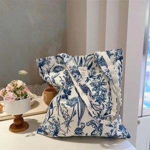 Detailed close-up of a botanical tie-dye canvas tote bag with floral patterns on a table